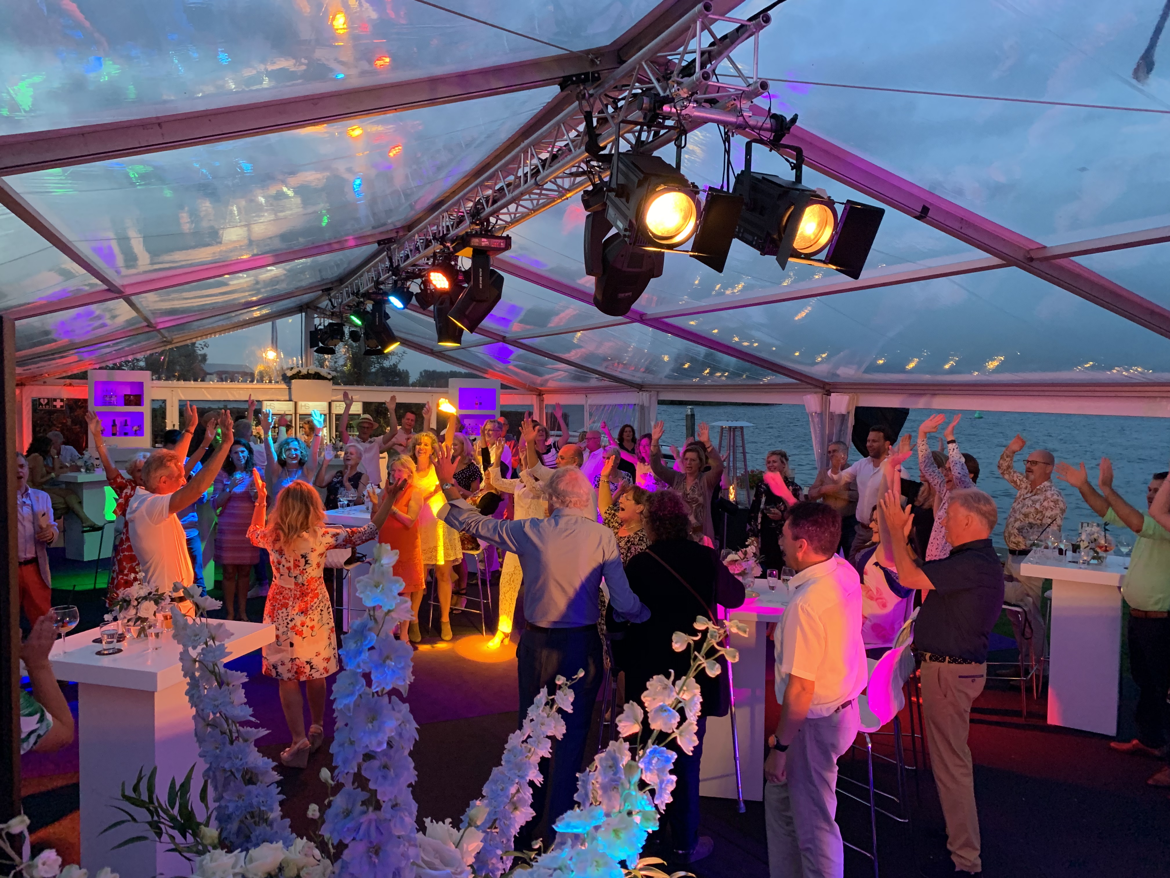 Gasten luisteren naar spreker tijdens netwerkborrel in een sfeervolle tentlocatie